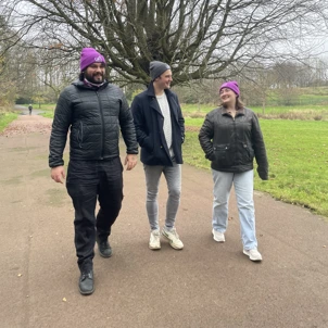 Three people walking outdoors wearing beanie hats