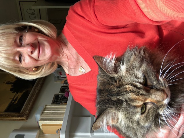 woman with short blonde hair wearing red jumper with brown tabby cat on her lap