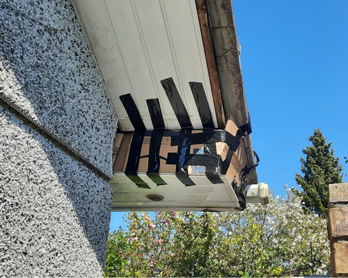 A hole in the underside of a roof that has been boarded and taped up