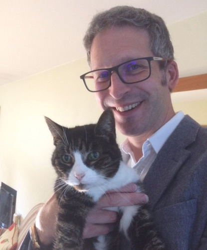 man with short grey hair holding brown-and-white tabby cat