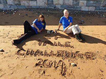 Two women in Cats Protection t-shirts sitting on the beach