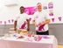 Two men wearing Cats Protection t-shirts standing behind a cake stall