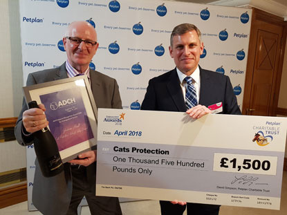 two men holding a large cheque, award and bottle of bubbly