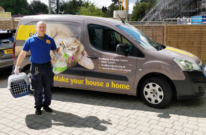 Cats Protection volunteer carrying cat carrier in front of Cats Protection van