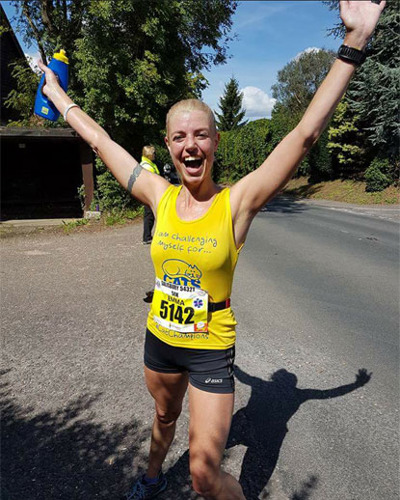 woman celebrating marathon run in Cats Protection vest