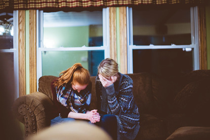 two women upset sitting on brown sofa