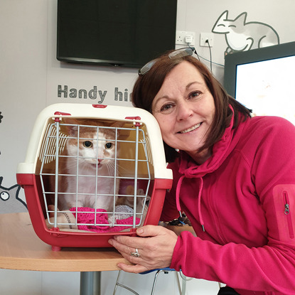 brunette woman with cat carrier containing a white and ginger cat