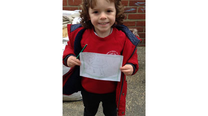 Little boy in school uniform holding drawing of cat