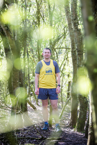 man standing in woods wearing Cats Protection running vest