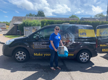 Cats Protection volunteer holding cat basket next to Cats Protection van