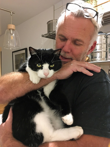 grey-haired man holding black-and-white cat