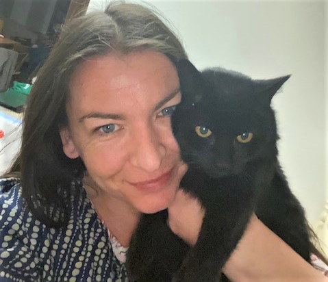 long-haired brunette woman holding black cat