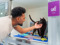 A man stroking the chin of a black cat in a cat pen
