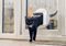 A black-and-white cat halfway through a cat flap in a glass door