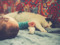 A black-and-white cat relaxing on a bed next to a baby lying nearby.