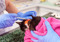 A black-and-white cat wrapped in a pink towel being vaccinated with a needle