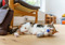 A calico cat lying on their side on the floor clutching a mouse-shaped cat toy in their front paws