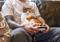 Calico cat sitting on a person's lap while the person holds a game controller.
