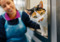 A calico cat peering out of a cat pen with a Cats Protection employee behind them
