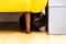 black cat hiding under yellow sofa