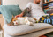 A calico cat lying on a grey sofa and being stroked by a man sitting next to them